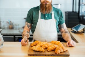 chef with tattoos displays croissants