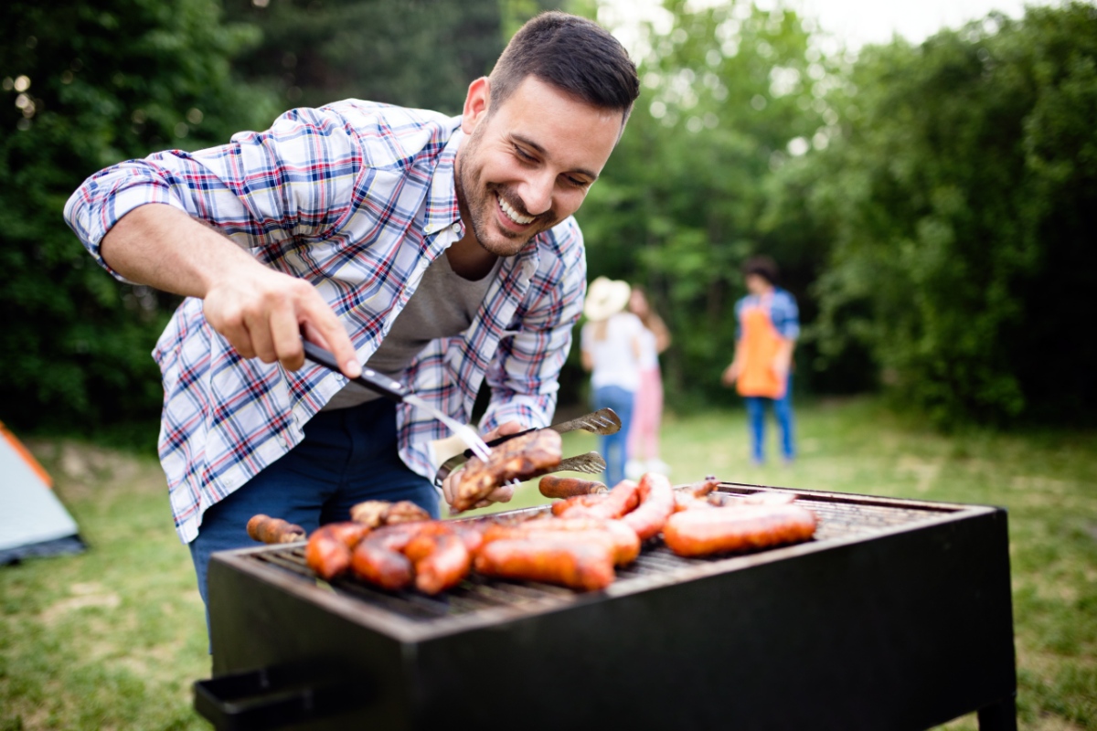 man grilling hot dogs outdoors