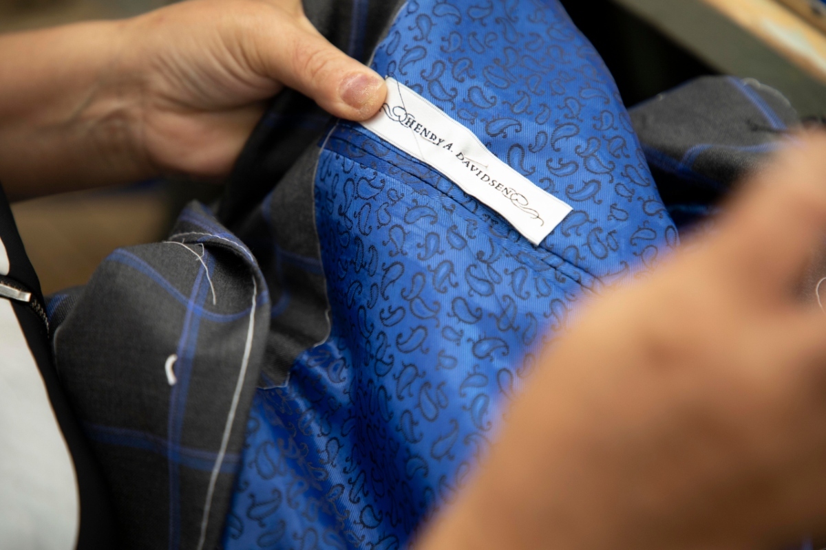 person sewing brand label into suit jacket