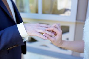 bride puts wedding ring on husband