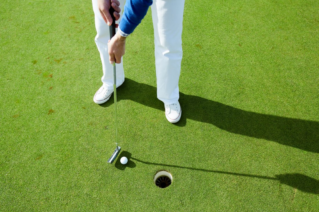 man in white pants golfing