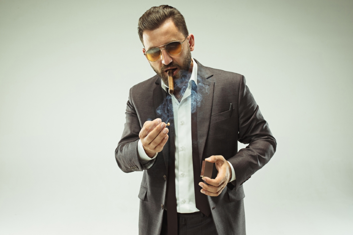 man with sunglasses lighting cigar