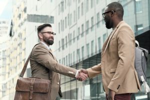 two men shake hands outdoors