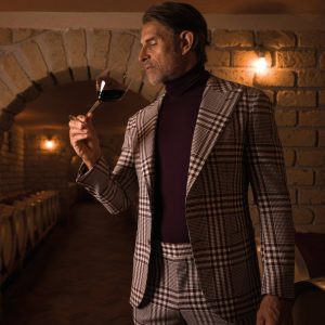 man in custom suit tastes wine