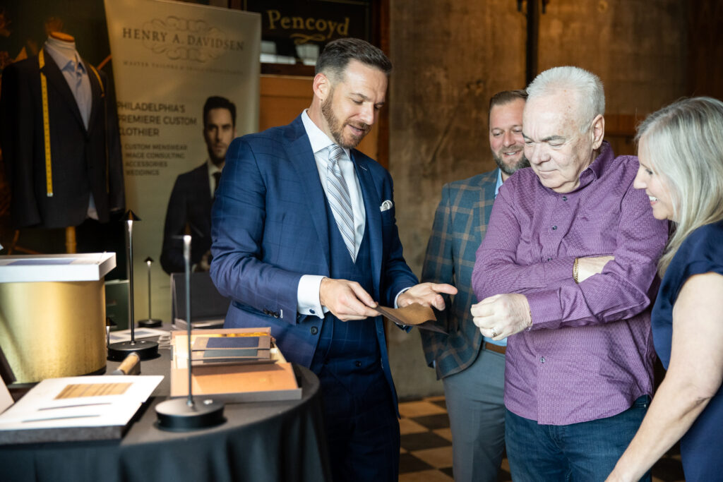 Custom menswear tailor shows clients a cut of fabric
